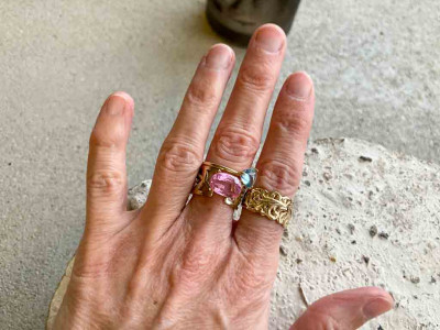 Hand zeigt Goldring mit pinkfarbenem Saphir